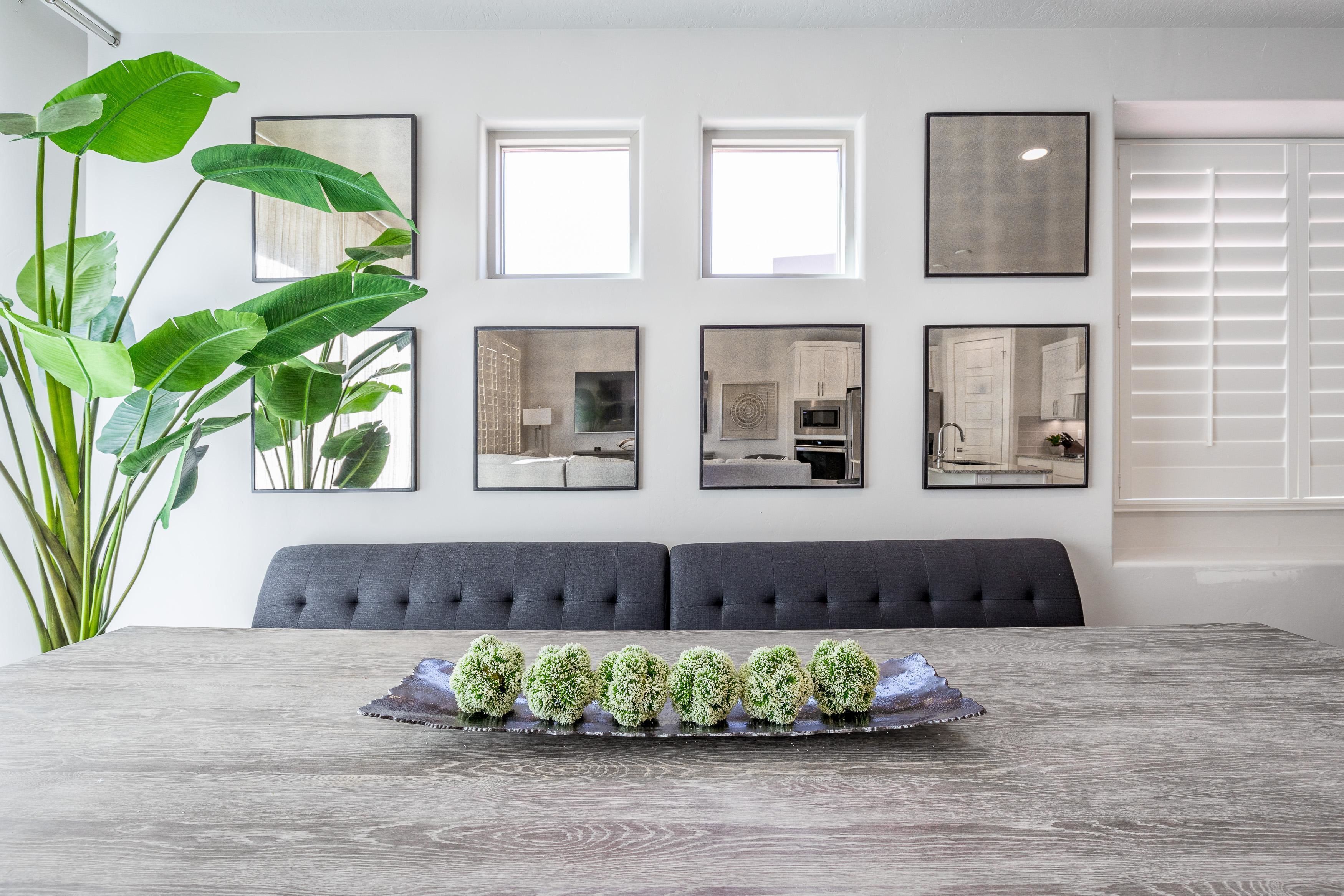 A dining area with a wooden table, a grey upholstered bench, and a tray of decorative green spheres.