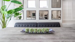 A dining area with a wooden table, a grey upholstered bench, and a tray of decorative green spheres. - Desert Solace (St. George)