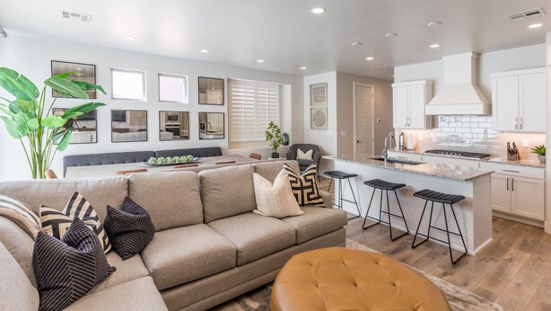 A modern living room with a beige sofa, a coffee table, and a bar area with stools. - Desert Solace (St. George)