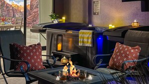 Zona de spa con un jacuzzi, asientos con almohadones, un hogar y vistas a un paisaje montañoso.