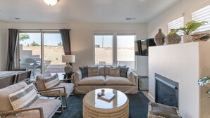 Ein Wohnzimmer mit einer Couch, Sesseln, einem Couchtisch und einem Kamin.