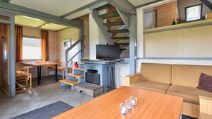 Un espacio de sala acogedor con chimenea, un sofá, una mesa de centro y un televisor.