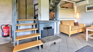 Un interior moderno con chimenea de piedra, escalera de madera y una zona de estar acogedora.