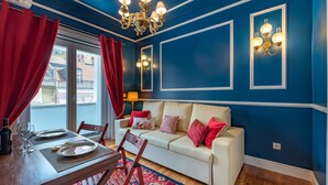 A dining area with a table set for two, a sofa, and a chandelier. - Modern stylish studio in downtown Lisbon center - new to Vrbo (Lisboa)