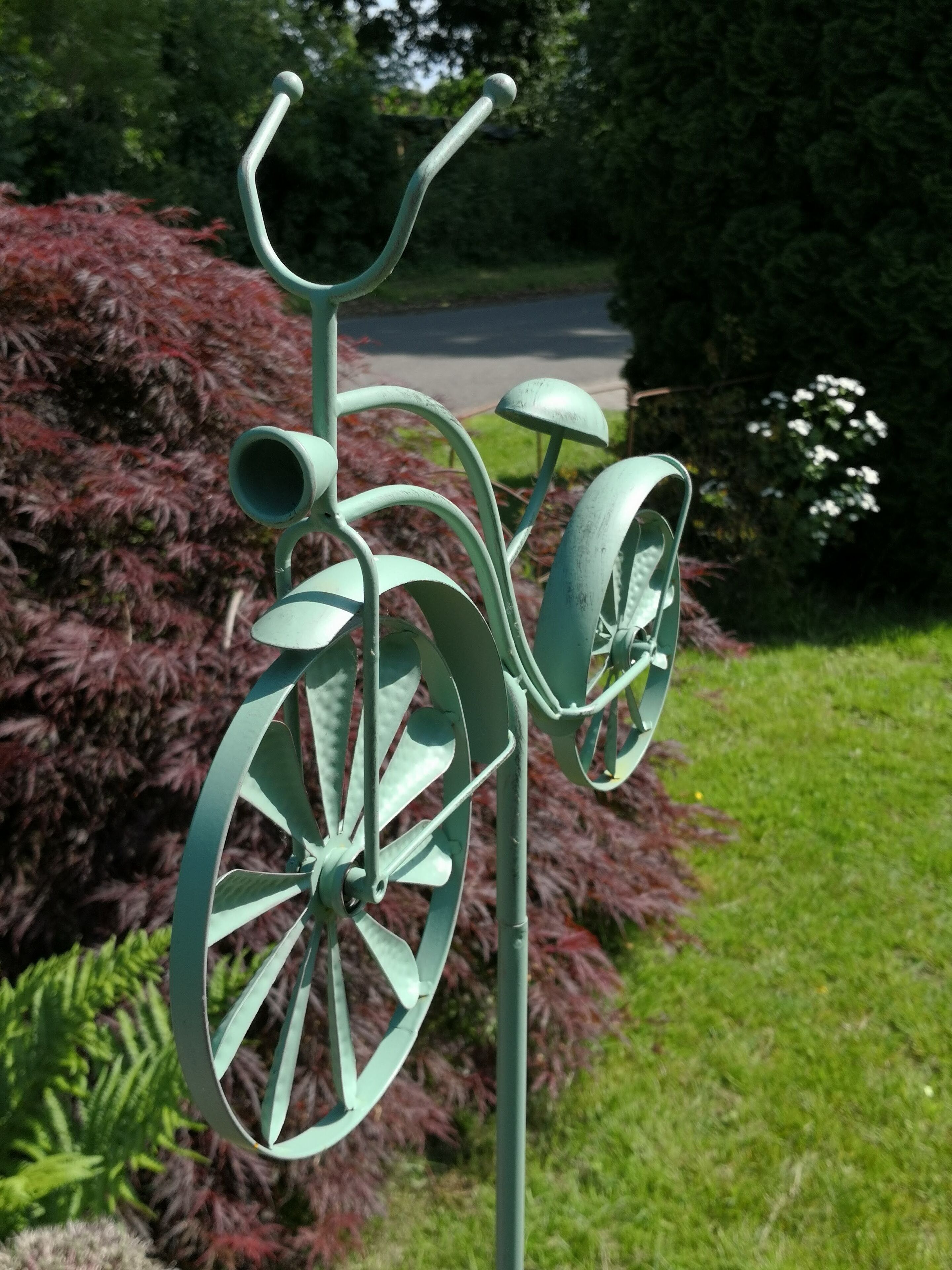Una scultura in metallo raffigura una bicicletta in un giardino.