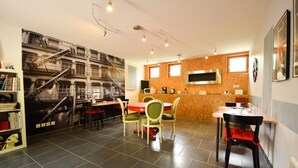 A modern kitchen with a microwave, coffee maker, and a large window. There is a dining area with a red table and green chairs. - Standard double room "B" (Bruyères-et-Montbérault)