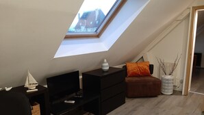 A loft bedroom with a skylight, a desk, a chair, a sofa, and a decorative vase. - Standard double room "B" (Bruyères-et-Montbérault)