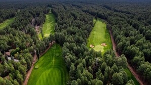 Ilmakuva golfkentästä, jota ympäröi tiheä metsä.