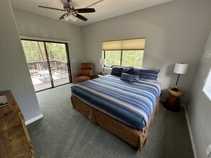 Relax in this serene bedroom with a large bed, ceiling fan, and comfortable seating area.