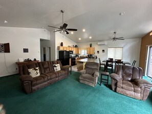 Relax in this stylish living area with a brown leather sofa, armchair, and recliner, surrounded by a vibrant carpet and modern decor.