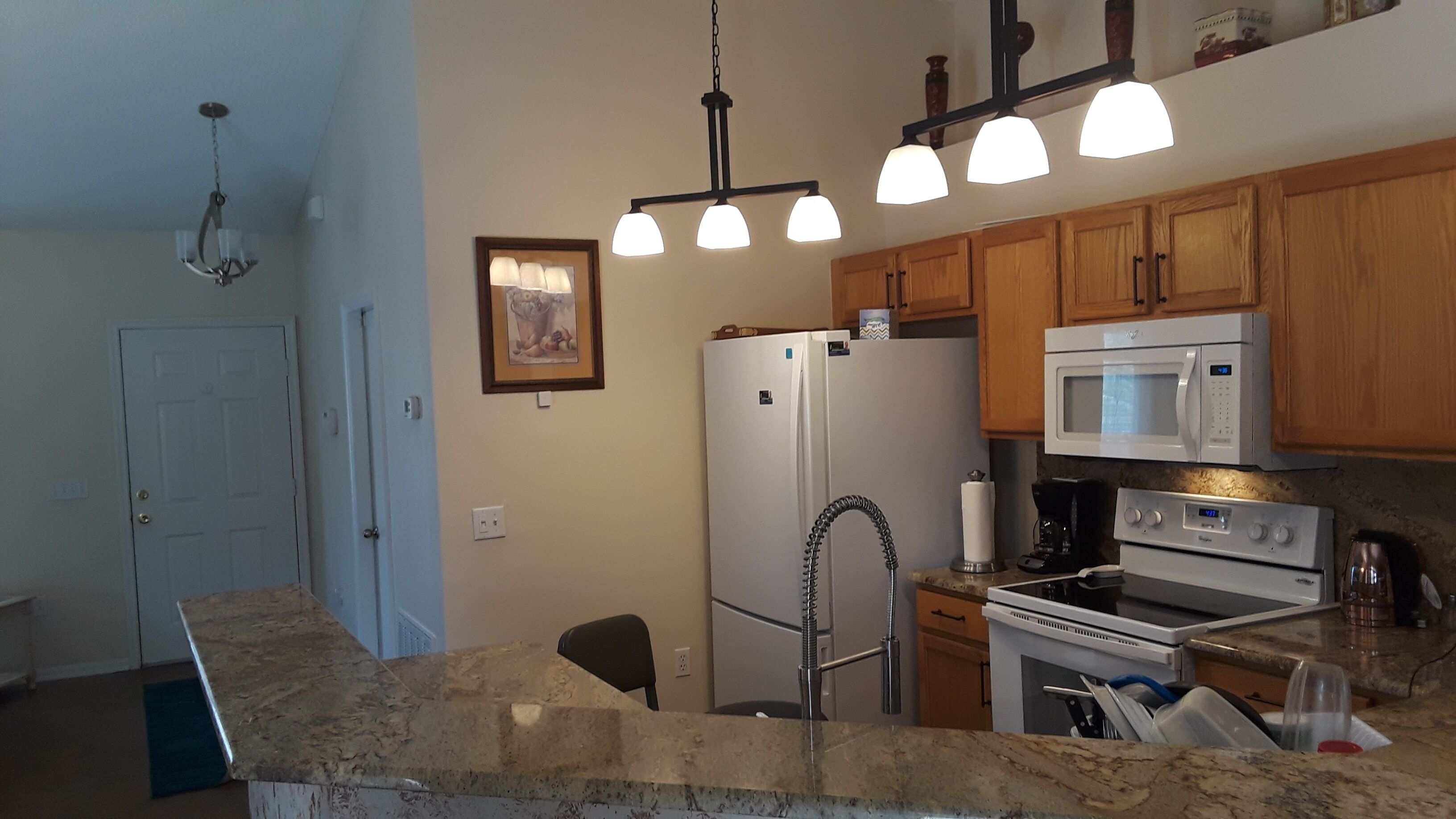 A kitchen with granite countertops, a refrigerator, a microwave, an oven, and a sink.