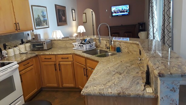 A kitchen with granite countertops, wooden cabinets, a stainless steel sink, and a built-in oven. - Beautiful 4 BR/2BA Private Pool Home Near Weeki Wachee Springs (Spring Hill, Florida, 34608)