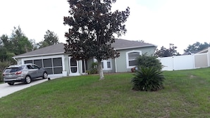 A residential house with a driveway, a tree, and a small bush. - Beautiful 4 BR/2BA Private Pool Home Near Weeki Wachee Springs (Spring Hill, Florida, 34608)