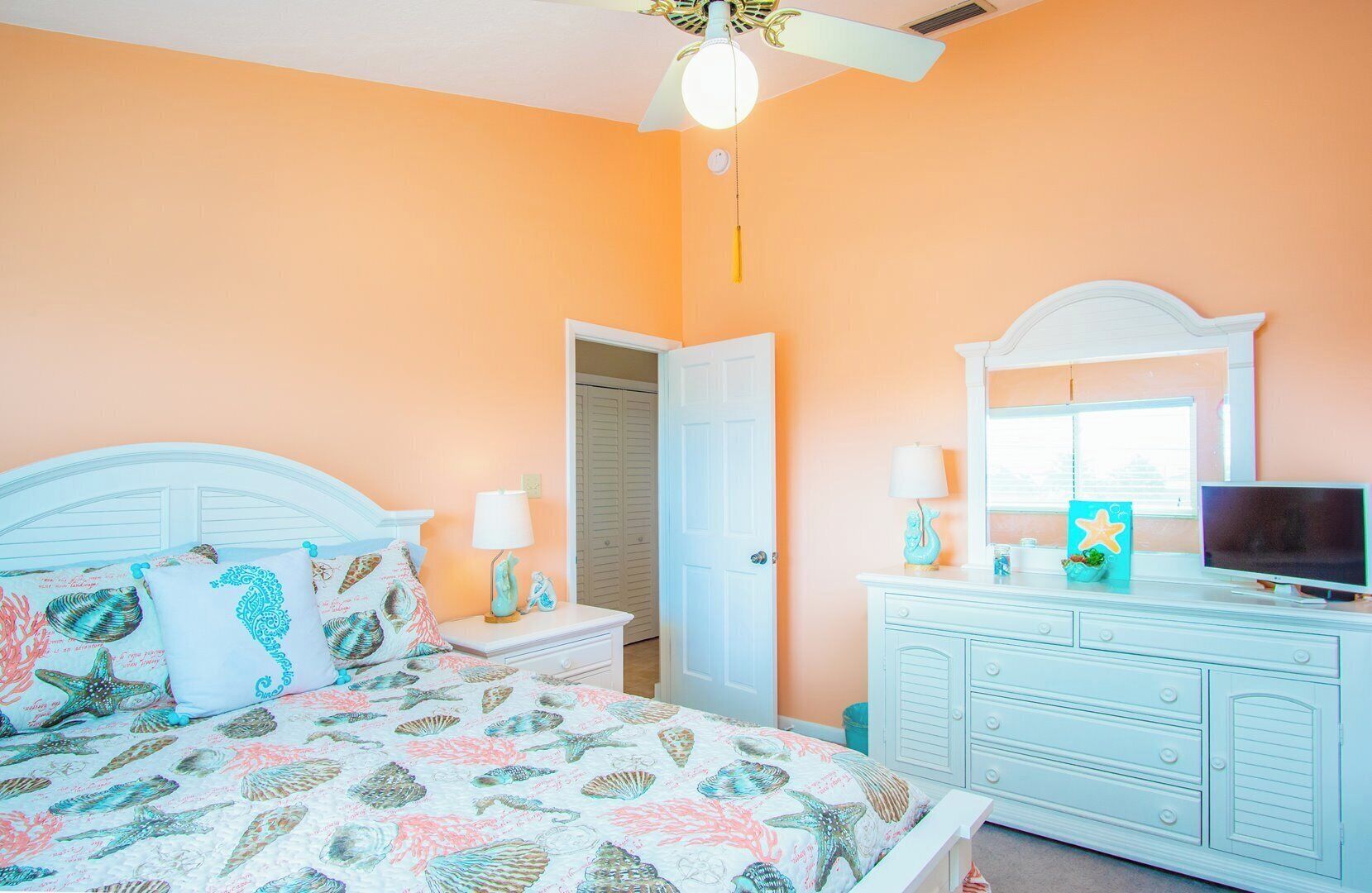A bedroom with a bed, nightstands, a dresser, a television, and a ceiling fan.