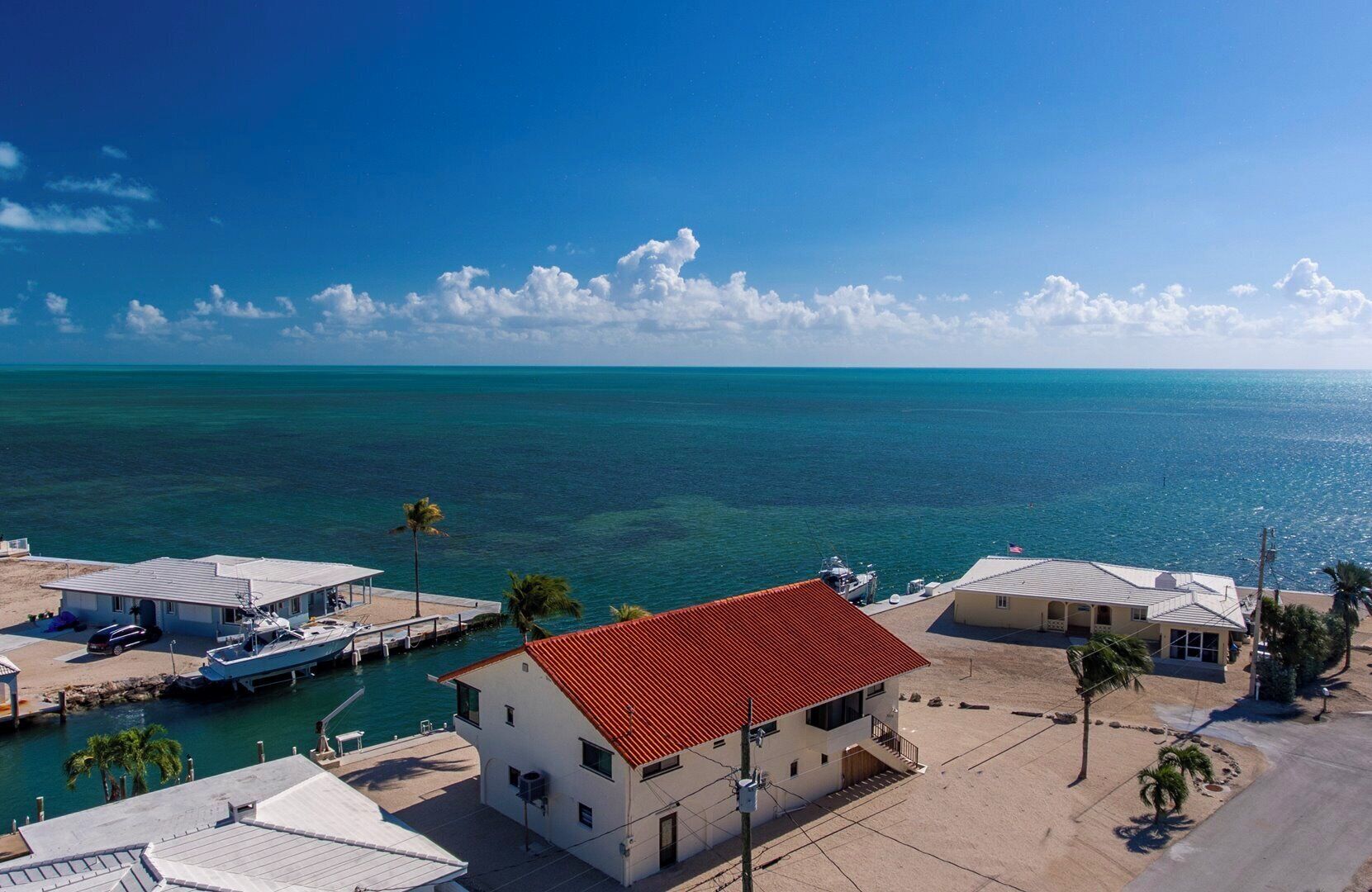 Une propriété située sur la côte, dotée d’un port de plaisance, d’une maison avec un toit rouge et offrant une vue dégagée sur l’océan.