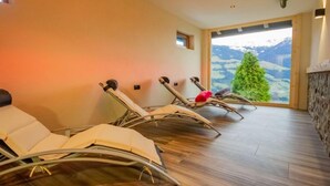 Un cuarto de spa con sillones reclinables, una chimenea de piedra y vistas a un paisaje montañoso.