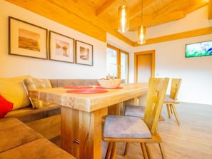 Ein modernes Wohnzimmer mit Holzboden, einem Esstisch mit Stühlen und gerahmten Bildern an der Wand.