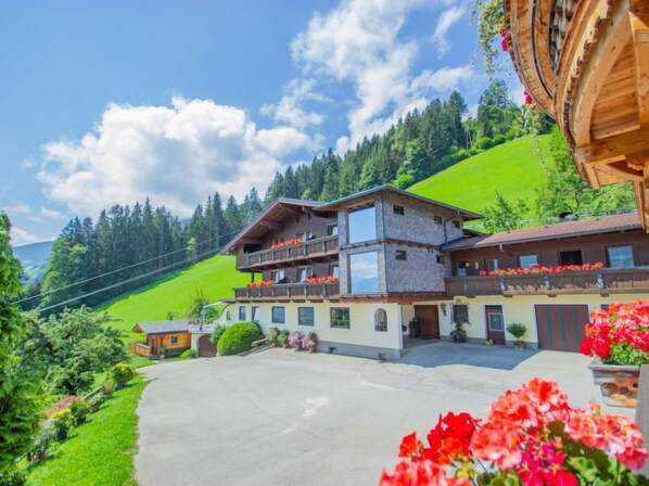 A two-story chalet with balconies, surrounded by lush greenery and a clear sky. - Brandegg Top 3 by Interhome (Fügen)