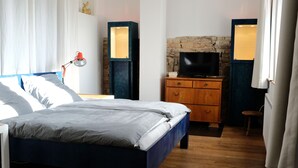 A bedroom with a bed, a dresser, a television, and a lamp.