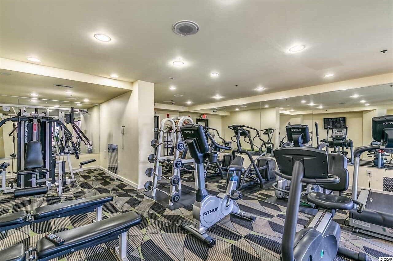 Et fitnesscenter med forskellig træningsudstyr, herunder løbebånd, crosstrainere og styrkemaskiner.