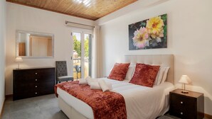 A bedroom with a bed, a nightstand, a dresser, a chair, a mirror, and a painting of flowers. - In pedestrianised Funchal Old Town | Taberna Apt 5 (Funchal)