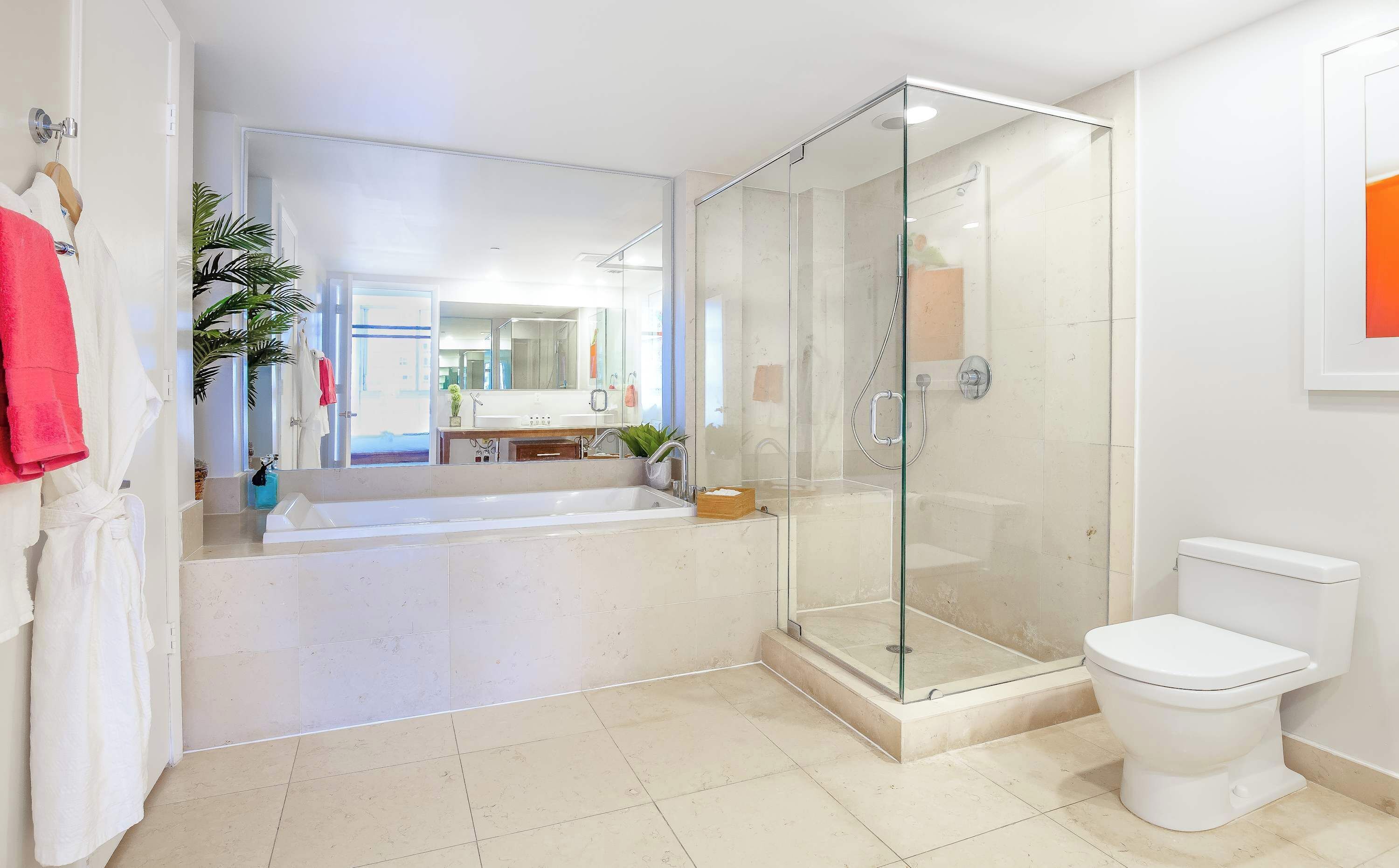 A modern bathroom with a glass-enclosed shower, a white toilet, and a large mirror.