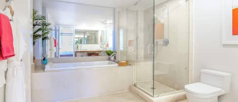 A modern bathroom with a glass-enclosed shower, a white toilet, and a large mirror.