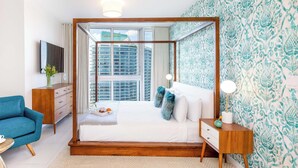 Un dormitorio moderno con una cama con dosel, una mesita de noche de madera, un sillón azul y un ventanal con vistas a la ciudad.