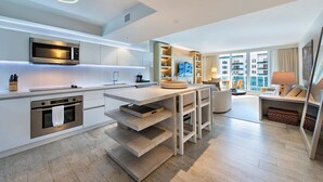 Una cocina moderna con electrodomésticos integrados, una isla central y un área de comedor con sofá y mesa.