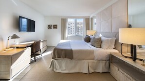Una habitación de hotel moderna con una cama grande, un escritorio, una silla, un televisor y una ventana con vista a la ciudad.