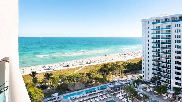 Un hotel con piscina, vistas a la playa y varios balcones.