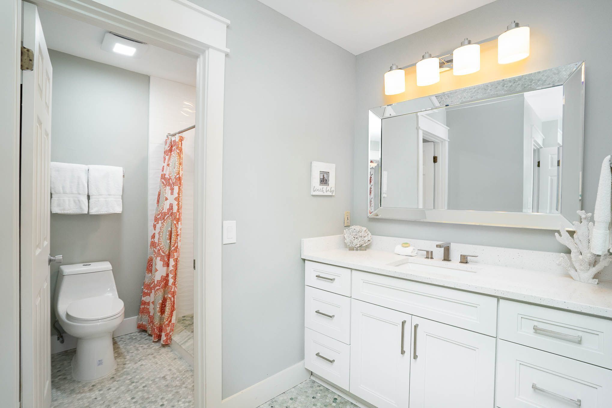 Une salle de bain comprenant des toilettes, un lavabo avec un miroir et un rideau de douche.