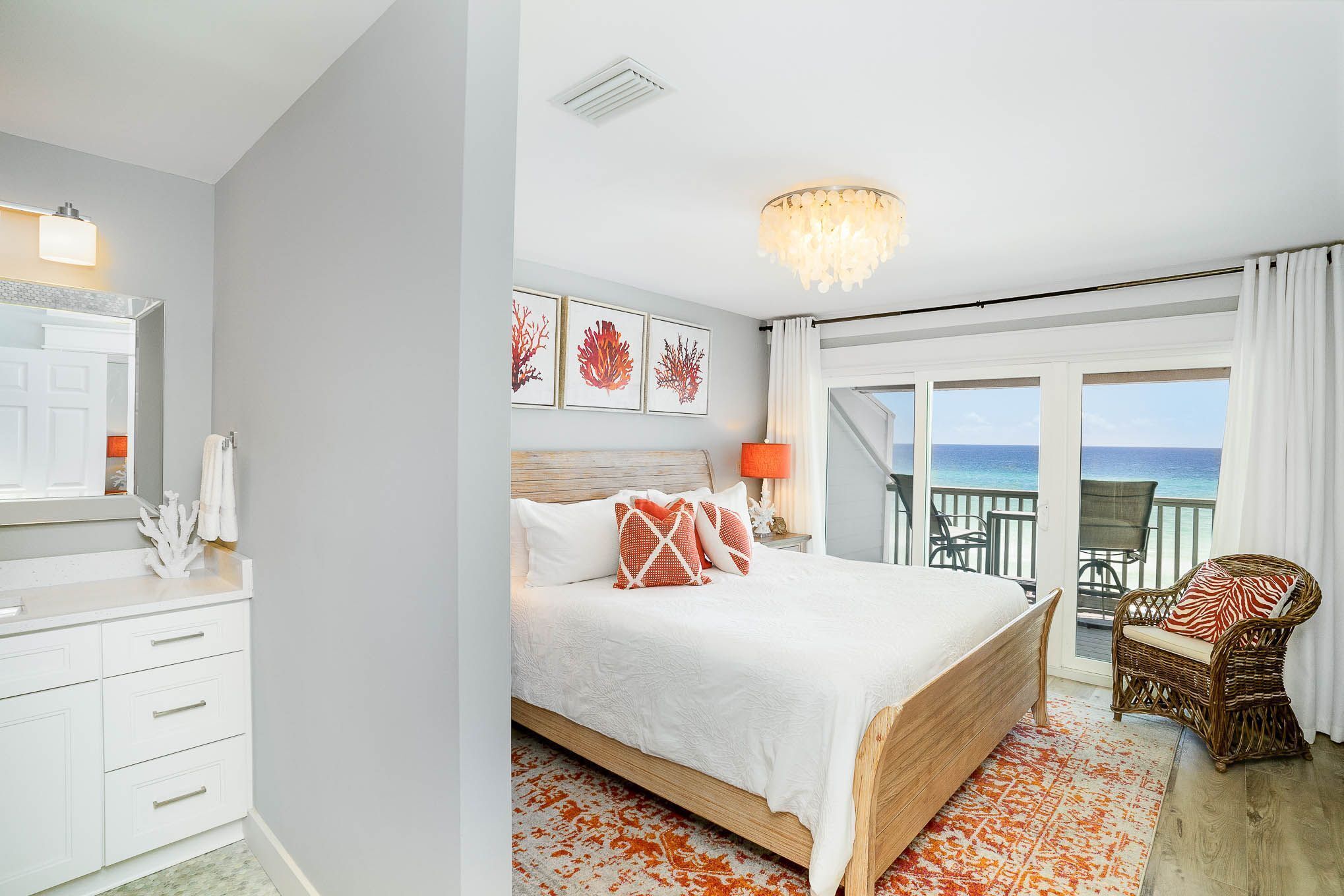 Een slaapkamer met een groot bed, een nachtkastje, een stoel en uitzicht op de oceaan door een schuifdeur.