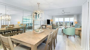 Un vaste espace de vie comprenant une table à manger en bois, des sièges confortables, une grande fenêtre offrant une belle vue et un ventilateur de plafond.