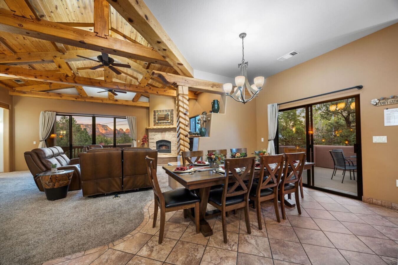 A spacious living area with a fireplace, wooden ceiling beams, and a dining table set for six.