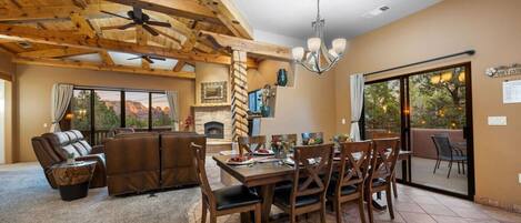 A spacious living area with a fireplace, wooden ceiling beams, and a dining table set for six.