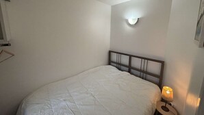 A bedroom with a single bed, a bedside lamp, and a wall-mounted light fixture. - Cozy 1BR Apartment for 4 with Balcony & Parking, 450m from Lifts – L'Alpe d'Huez (Huez)