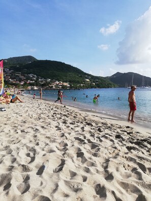 Ein Strand mit Schwimmern und Menschen, die am Ufer entlanggehen.