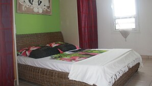 Un dormitorio con cama, paredes verdes, una ventana con cortina y un cuadro en la pared.