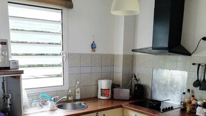 Una cocina con ventana, un lavabo, una estufa y una lámpara colgante.