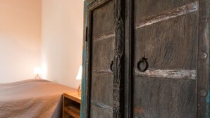 A wooden door with a rustic design, a bed with a beige blanket, and a bedside table with a lamp. - Aurore du Lac - Duplex Apartment 4pers. + Studio 2pers. (Sevrier)