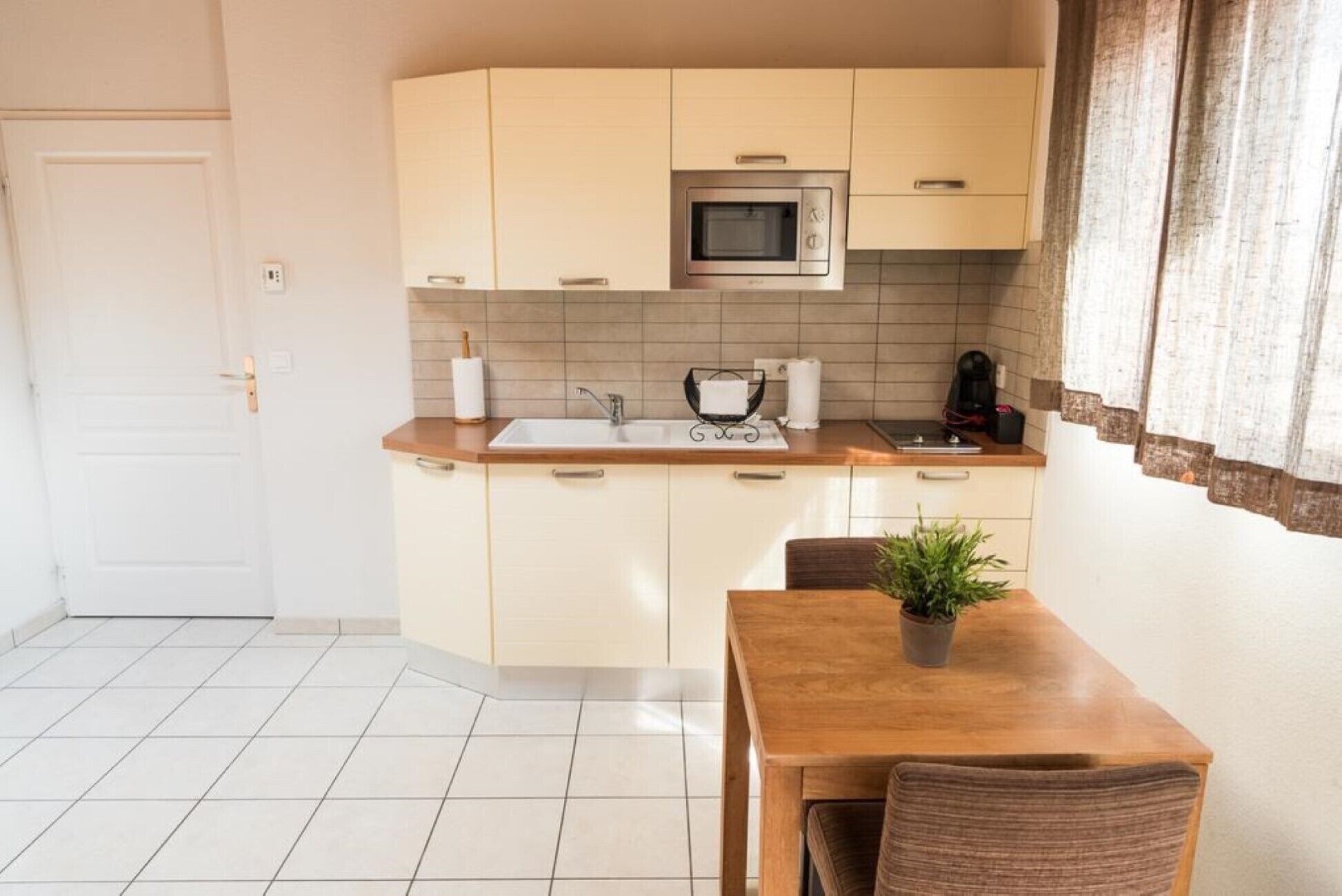 A compact kitchen with a microwave, sink, and a dining area with a table and chairs.