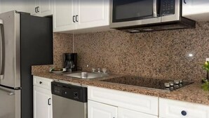 Een moderne keuken met roestvrijstalen apparatuur, granieten werkbladen en witte keukenkastjes.