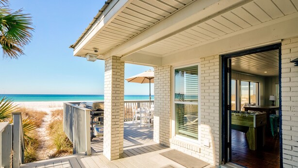 Une maison de plage dotée d’une terrasse en bois, d’un patio couvert et d’une vue sur l’océan.