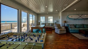 Un salon spacieux avec une table de baby-foot, un canapé, une table basse et une vue sur la plage.