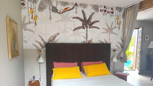 Un dormitorio con cama, almohadas, mesita de noche, lámpara, cuadro y ventana con cortinas.
