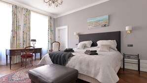 Un dormitorio con una cama grande, un escritorio, una silla y una araña.