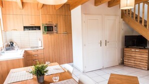 Une cuisine moderne avec des meubles en bois, un four à micro-ondes et un coin repas avec une table dressée pour deux personnes.