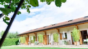 Un bâtiment doté d’un patio couvert, de poutres en bois et d’un espace extérieur aménagé pour s’asseoir.