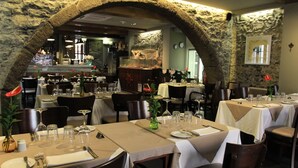 A restaurant with stone arches, tables set with white tablecloths, and a bar area in the background.